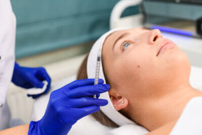 Beautician hold syringe for young female client