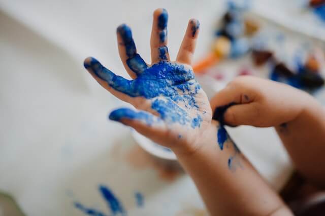 child with blue paint on hands